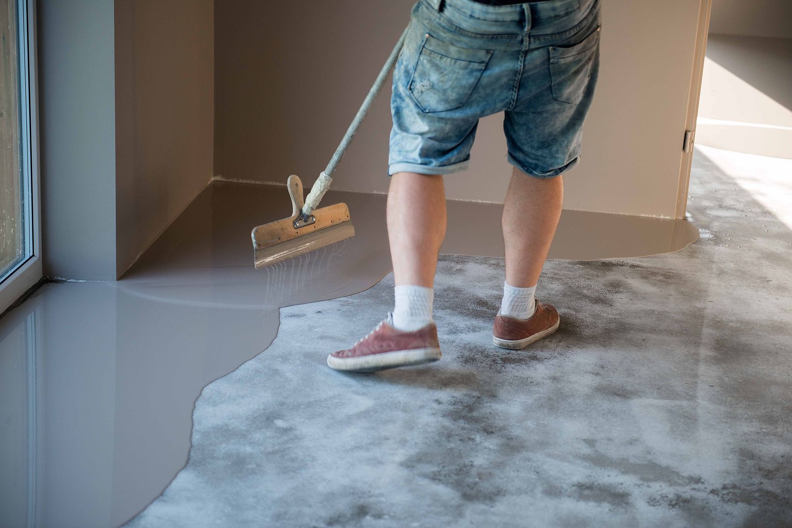 Installer spreading grey epoxy in a room